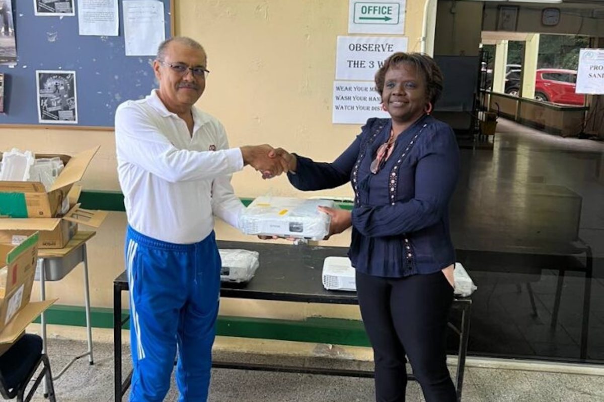 Manager of Terminix La Horquetta Rangers Richard Ferguson, left, presents a projector to Trinity College acting principal Ann Niles.