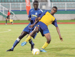 AT BAY: Shiva Boys Hindu College player Judah Peters, right, holds off a challenge from a Naparima College player during the Coca Cola Secondary Schools Football League South Zone InterCol final, at Manny Ramjohn Stadium, Marabella, yesterday. Naparima won 2-0. —Photo: NICHOLAS RAMJASS