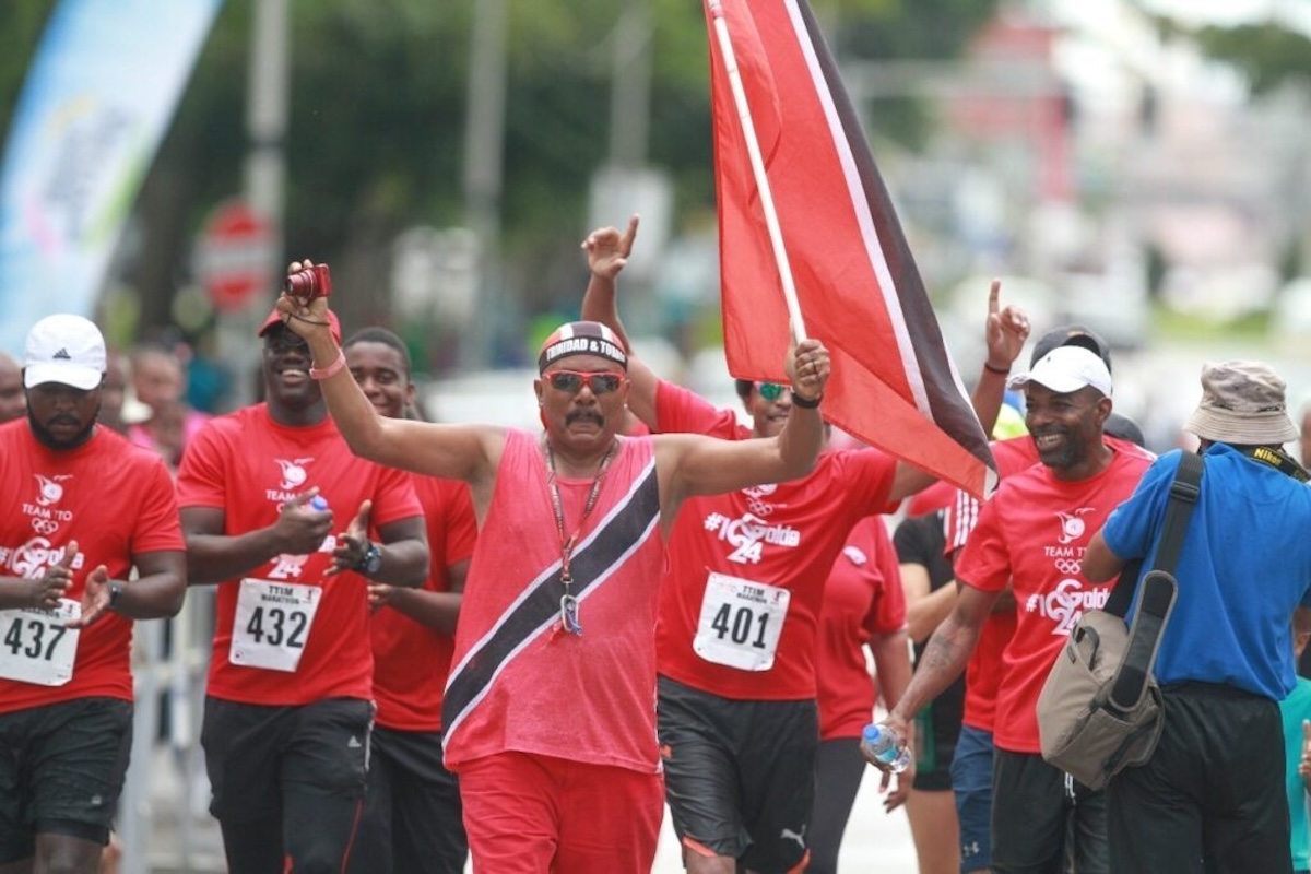 Joey "Flagman" Richardson, front, walks with Brian Lewis, T&T Olympic Committee immediate past president and others seeking to raise funds for national athletes.